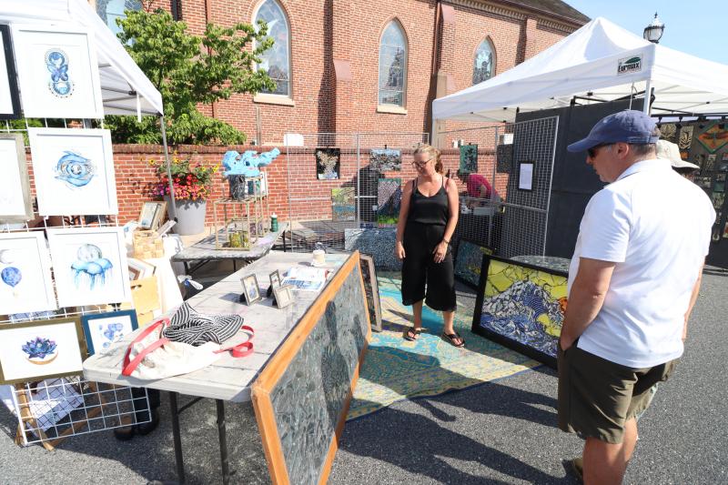 Mosaic artist Jenn Wagner, center, of St. Michael’s, Md., talks with some prospective customers about her work.